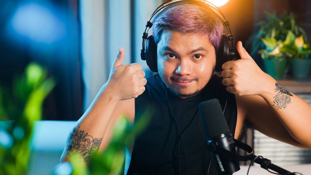 A man with purple hair giving the thumbs up